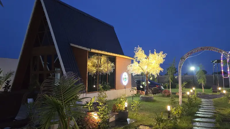A-frame with a glowing tree and lit garden path at blue hour