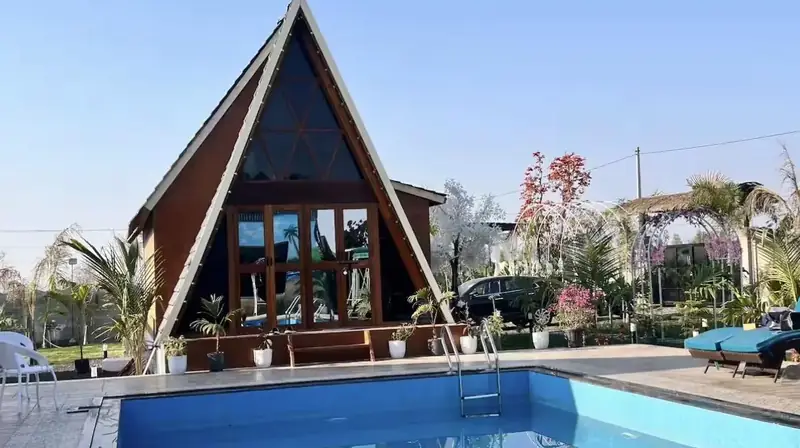 An A-frame cottage across the pool in daylight