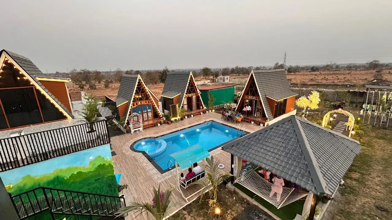 The whole property from above at dusk: four A-frames, pool, gazebo and lawn