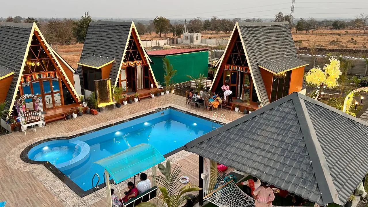Cottages outlined in fairy lights around the pool at dusk, with guests on the deck