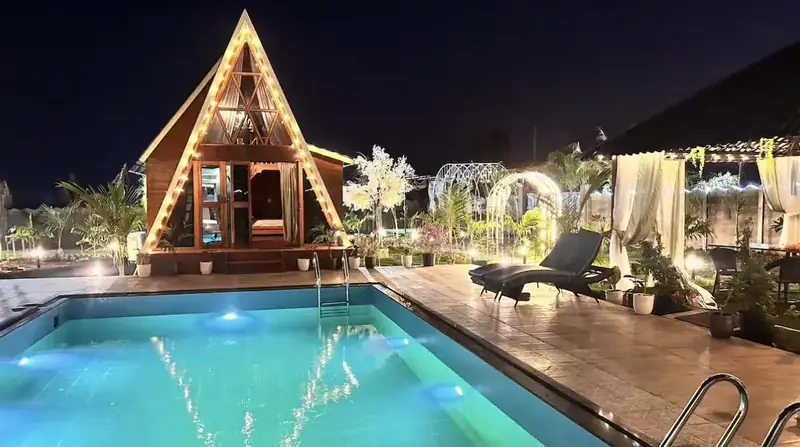 A lit A-frame reflected in the pool